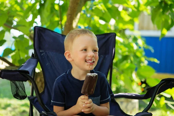 Felice ragazzo biondo mangiare gelato al cioccolato bar — Foto Stock
