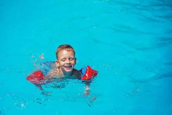 Niño feliz jugando en el agua azul de la piscina . —  Fotos de Stock