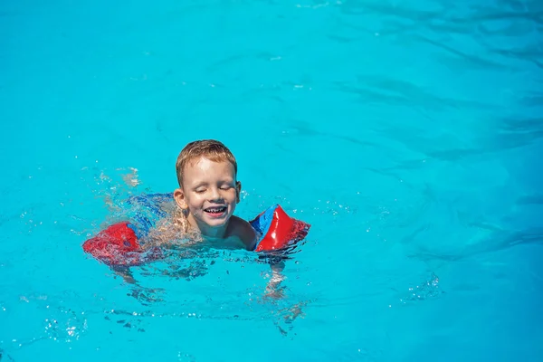 Niño feliz jugando en el agua azul de la piscina . — Foto de Stock