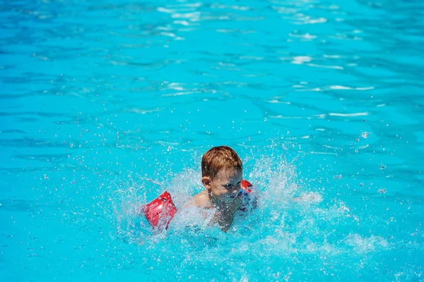 Gelukkig kind spelen in blauwe water van het zwembad. — Stockfoto