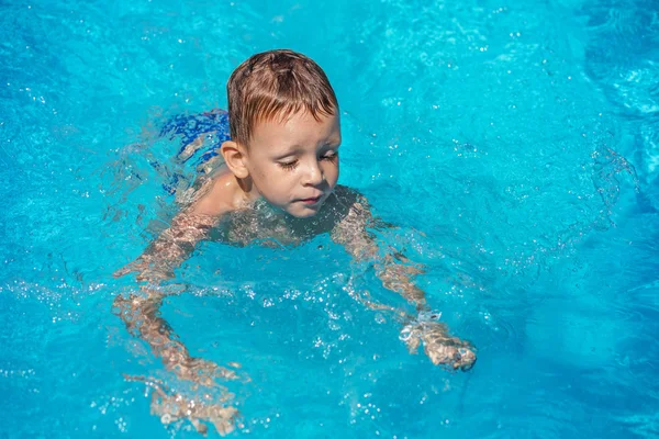 Niño feliz jugando en el agua azul de la piscina . — Foto de Stock