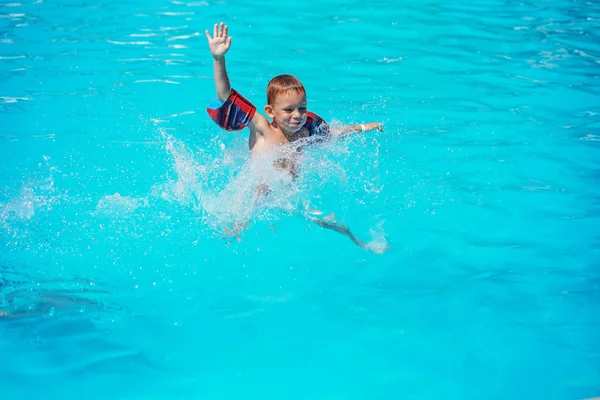 スイミング プールの青い水で遊んで喜んでいる子供. — ストック写真