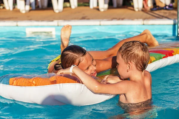 Šťastné děti, které hrají v modré vodě plaveckého bazénu. — Stock fotografie