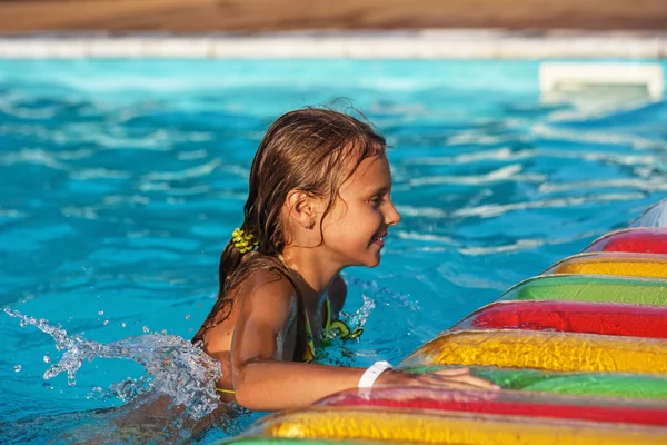 Gelukkig meisje spelen in blauw water van zwembad. — Stockfoto