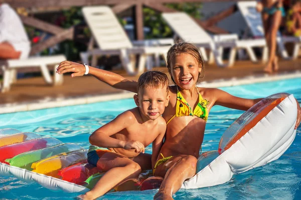 Crianças felizes brincando na água azul da piscina . — Fotografia de Stock