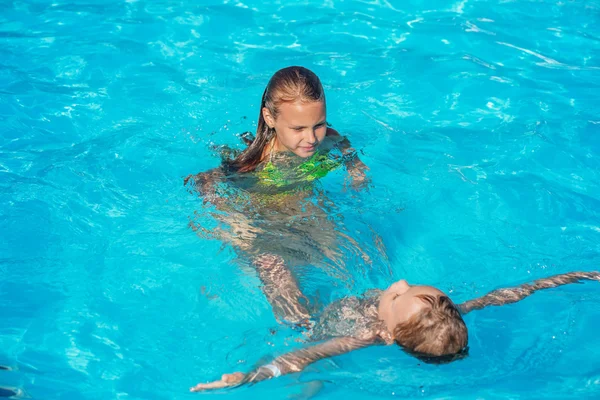 Gelukkige kinderen spelen in blauw water van het zwembad. — Stockfoto