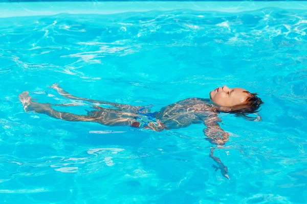 Счастливый ребенок играет в голубой воде бассейна . — стоковое фото