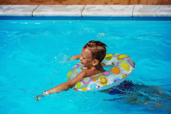 Счастливый ребенок играет в голубой воде бассейна . — стоковое фото
