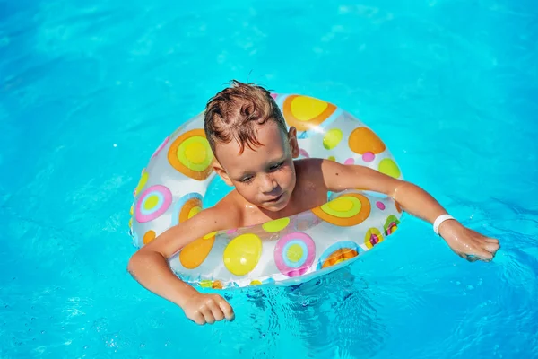 Criança feliz brincando na água azul da piscina . — Fotografia de Stock