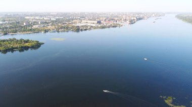 İnsansız hava aracı, çeşitli binaları ve bataklık habitatı olan ve Common Reed hava manzaralı yerel köyle çevrili bir nehrin üzerinde uçuyor. Üst görünüm.