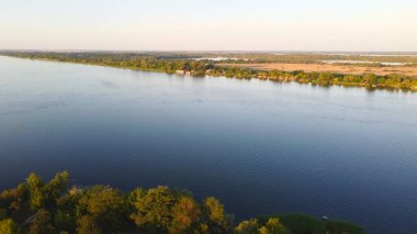 İnsansız hava aracı, çeşitli binaları ve bataklık habitatı olan ve Common Reed hava manzaralı yerel köyle çevrili bir nehrin üzerinde uçuyor. Üst görünüm.