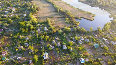 İnsansız hava aracı, çeşitli binaları ve bataklık habitatı olan ve Common Reed hava manzaralı yerel köyle çevrili bir nehrin üzerinde uçuyor. Üst görünüm.