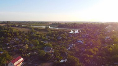 İnsansız hava aracı, çeşitli binaları ve bataklık habitatı olan ve Common Reed hava manzaralı yerel köyle çevrili bir nehrin üzerinde uçuyor. Üst görünüm.