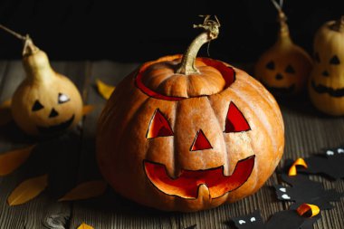 Balkabaklı Cadılar Bayramı tasarımı. Cadılar Bayramı 'nın korkunç sembolü, Jack-o-Lantern. Alevli korkunç balkabağı kafası ve birkaç küçük boyalı su kabağı. Parlayan yüz, şeker mi şaka mı? Cadılar Bayramı