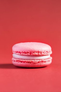 Kırmızı arka planda pembe pasta ya da badem kurabiyesi. Renkli bademli kurabiyeler. Fransız kurabiyeli keki yakın plan. Renkli arkaplanda makarnalar