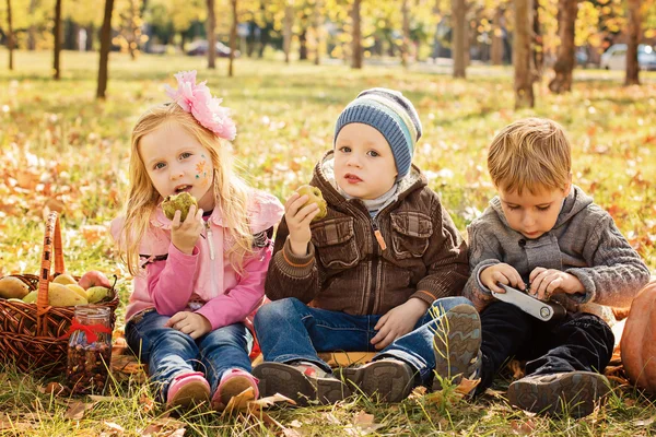 Tre bambini felici che giocano nel parco autunnale con la frutta — Foto Stock