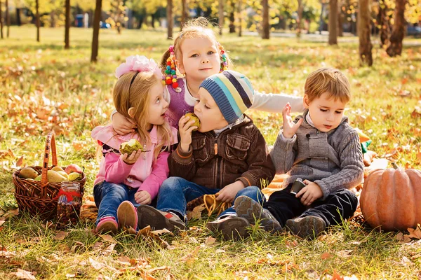 Vier glückliche Kinder spielen im Herbstpark mit Früchten lizenzfreie Stockfotos