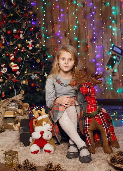 Niña esperando un milagro en las decoraciones navideñas — Foto de Stock