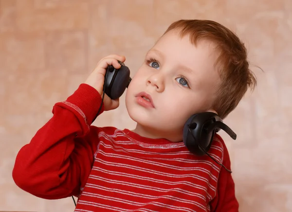 Niño pequeño con auriculares en casa — Foto de Stock