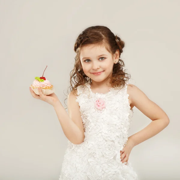 Little girl holding a delicious cake with cherry — Stock Photo, Image