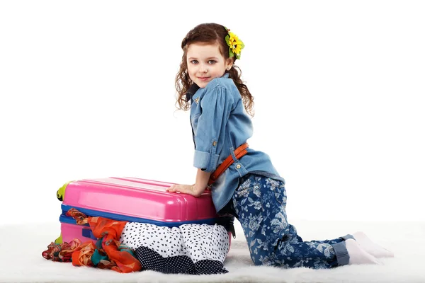 Модна маленька дівчинка закриває валізу одягом — стокове фото