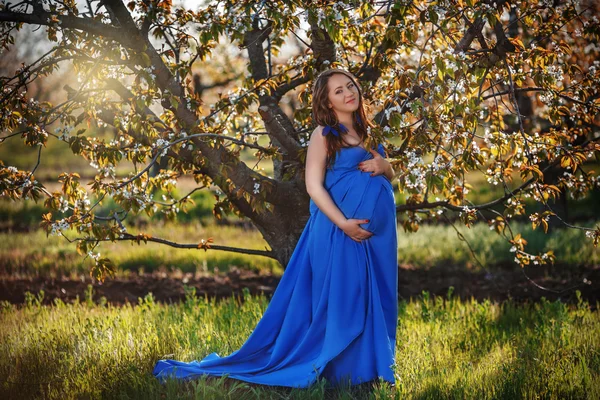 Hermosa mujer embarazada en el huerto en flor — Foto de Stock
