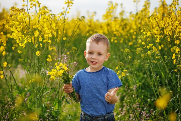 Little boy with a bouquet of flowers is in the yellow flowering — Stock Photo, Image