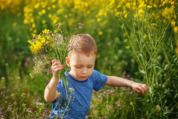 Menino bonito correndo com um buquê de flores em um me amarelo — Fotografia de Stock