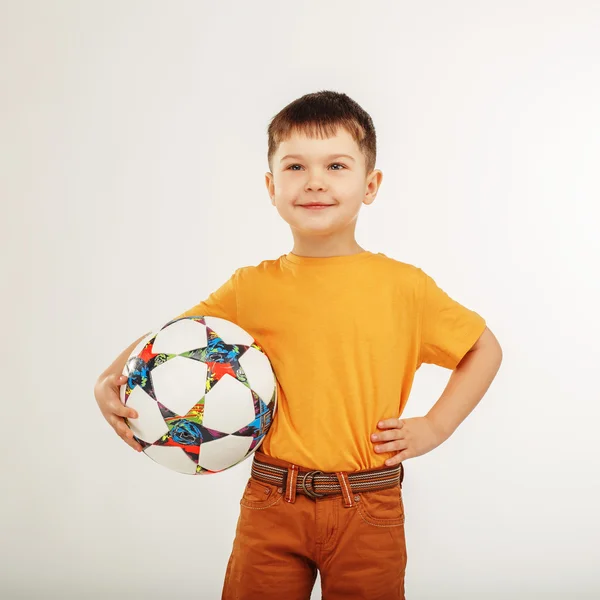 Niño pequeño sosteniendo una pelota de fútbol bajo su brazo — Foto de Stock