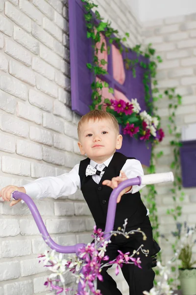 Portrait of an elegant young boy on a bicycle in studio decorate — Stock Photo, Image