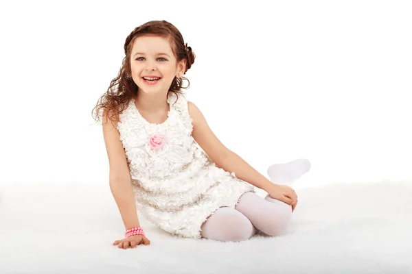 Portrait of a pretty little fun fashion girl sitting on a fluffy — Stock Photo, Image