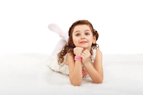 Porträtt av en söt liten rolig mode flicka liggande på en fluffig r — Stockfoto