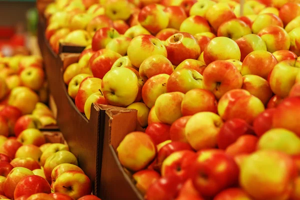 Многие спелые желто-красные яблоки в коробках в магазине — стоковое фото