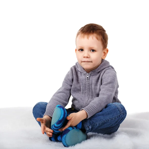 Pequeno menino bonito sentado no chão mordendo seu lábio inferior — Fotografia de Stock