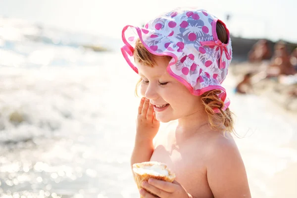 Маленькая девочка ест мороженое на пляже каникулы — стоковое фото