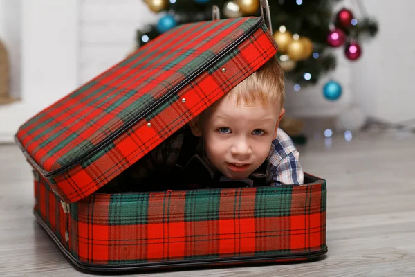 Kleiner Junge spielt Versteck in einem rot karierten Koffer — Stockfoto