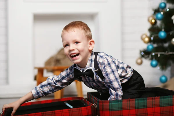 Niño jugando escondido en una maleta a cuadros roja en el interio —  Fotos de Stock
