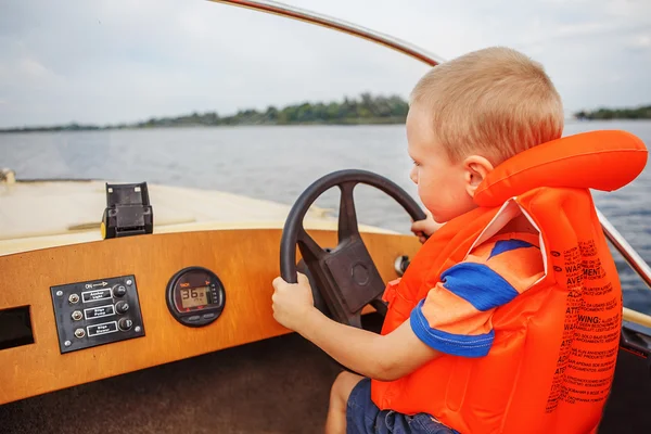 Küçük çocuk whee direksiyon sıkıca tutarak bir motorlu tekne sürüş — Stok fotoğraf