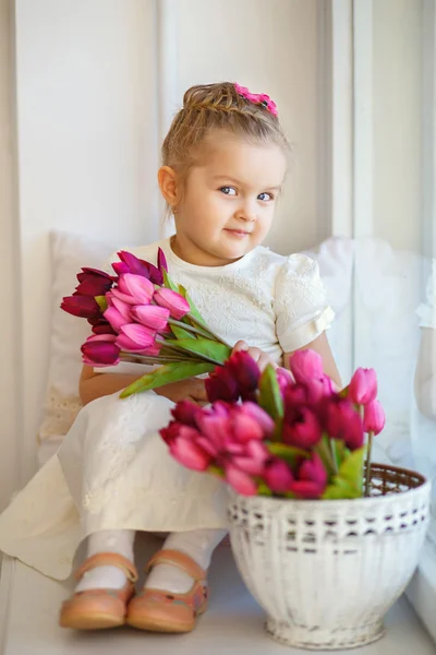 Belle petite fille dans une robe blanche assise sur un rebord de fenêtre w — Photo