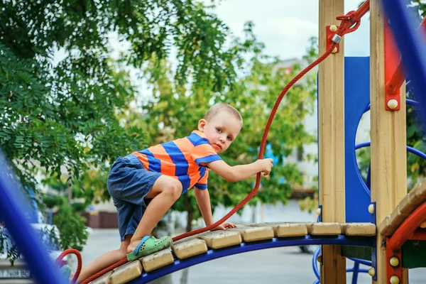 Schattige kleine jongen spelen op de speelplaats in de zomer — Stockfoto