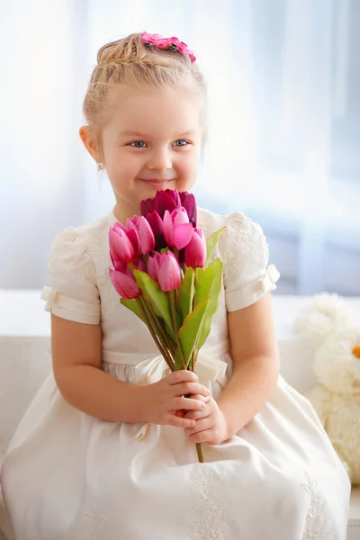 Linda menina em um vestido branco com um buquê de rosa tu — Fotografia de Stock