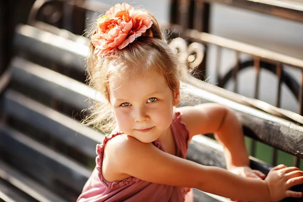 Retrato de uma menina bonita sentada em um banco de parque — Fotografia de Stock