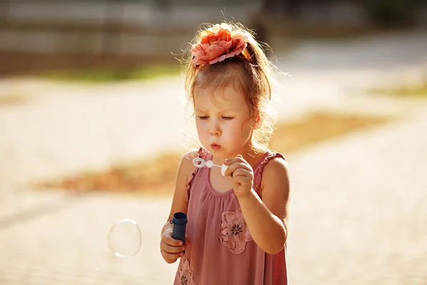 Niña soplando burbujas de jabón en el parque — Foto de Stock