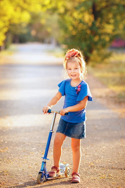 Porträtt av lekfulla kul leende liten flicka med skoter i den — Stockfoto