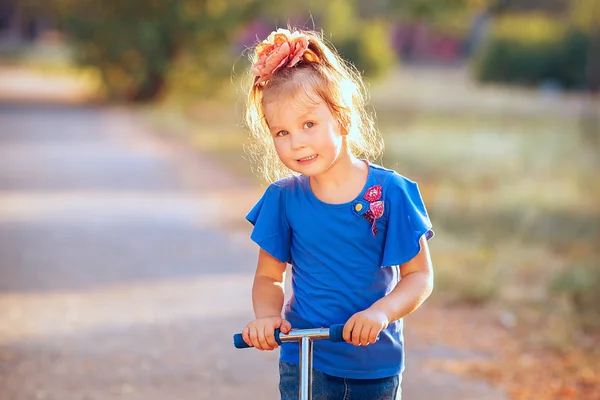 Portrait of playful fun smiling little girl with scooter in the — Stock Photo, Image