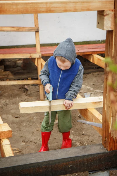 Rapaz estudioso a serrar uma tábua de madeira. Construção de casas. Li... — Fotografia de Stock