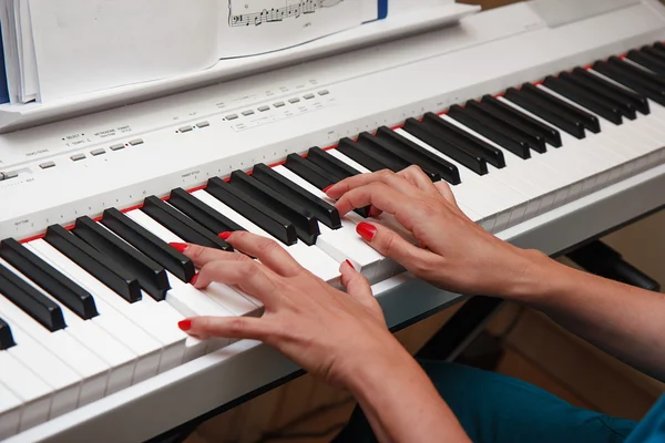 Händerna på en ung kvinna spela piano — Stockfoto