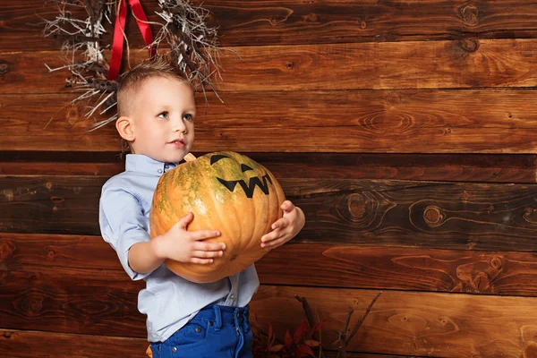 Halloween party with child holding painted heavy pumpkin — Stock Photo, Image