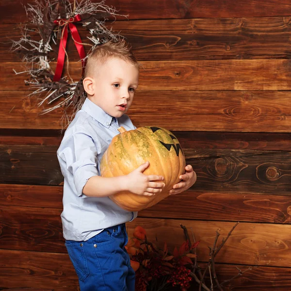 Halloween party with child holding painted pumpkin — Stock Photo, Image