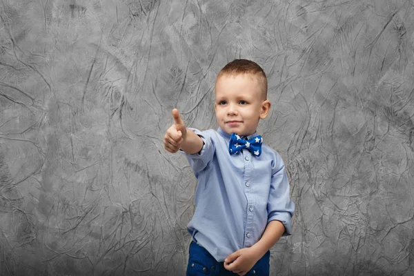 Портрет милого мальчика в джинсах, голубой рубашке и галстуке-бабочке — стоковое фото
